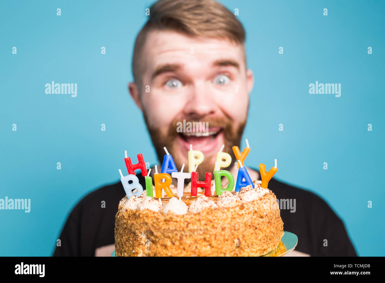 Crazy funny guy positivo hipster tenendo un buon compleanno torta nelle sue  mani in piedi su uno sfondo blu. Concetto di scherzi e i saluti delle  vacanze Foto stock - Alamy