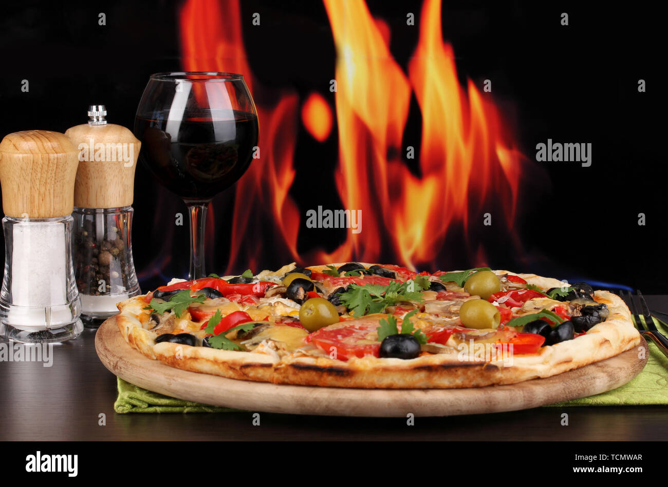 Una deliziosa pizza con un bicchiere di vino rosso e spezie su un tavolo di  legno sul fuoco sfondo Foto stock - Alamy