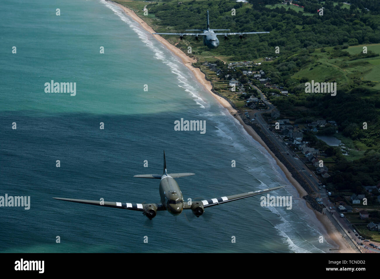 Un Douglas C-47 Dakota, soprannominato "che è tutto il fratello", vola con U.S. Air Force C-130J Super Hercules, assegnato per la trentasettesima Airlift Squadron, Ramstein Air Base, Germania, oltre la Normandia, Francia, giugno 8, 2019. Il C-130J portava segni di invasione, simile al suo squadrone legacy, la trentasettesima Troop Carrier Squadron, che ha volato missioni di combattimento durante il funzionamento Nettuno, Giugno 6, 1944. (U.S. Air Force foto di Senior Airman Devin M. Rumbaugh) Foto Stock