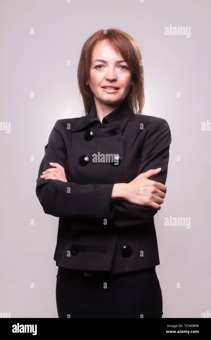 Una bella donna matura ritratto, 40-49 anni, con le braccia incrociate. Guardando alla fotocamera. Il corpo superiore shot, che indossa un semplice abito nero. Girato in Foto Stock