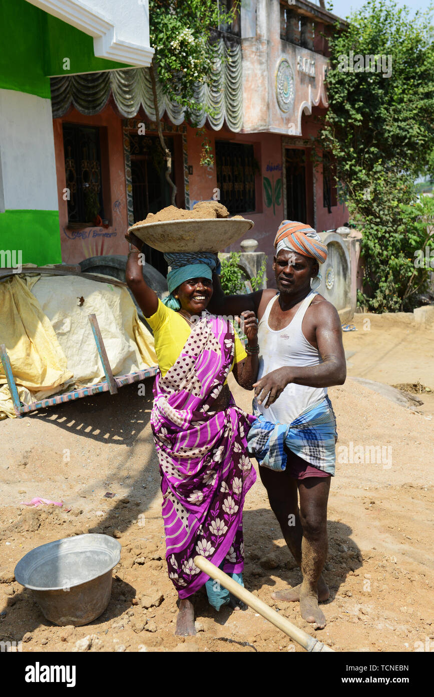 Un uomo Tamil caricamento di un cesto pesante di sabbia su un lavoratore di sesso femminile alla testa. Foto Stock