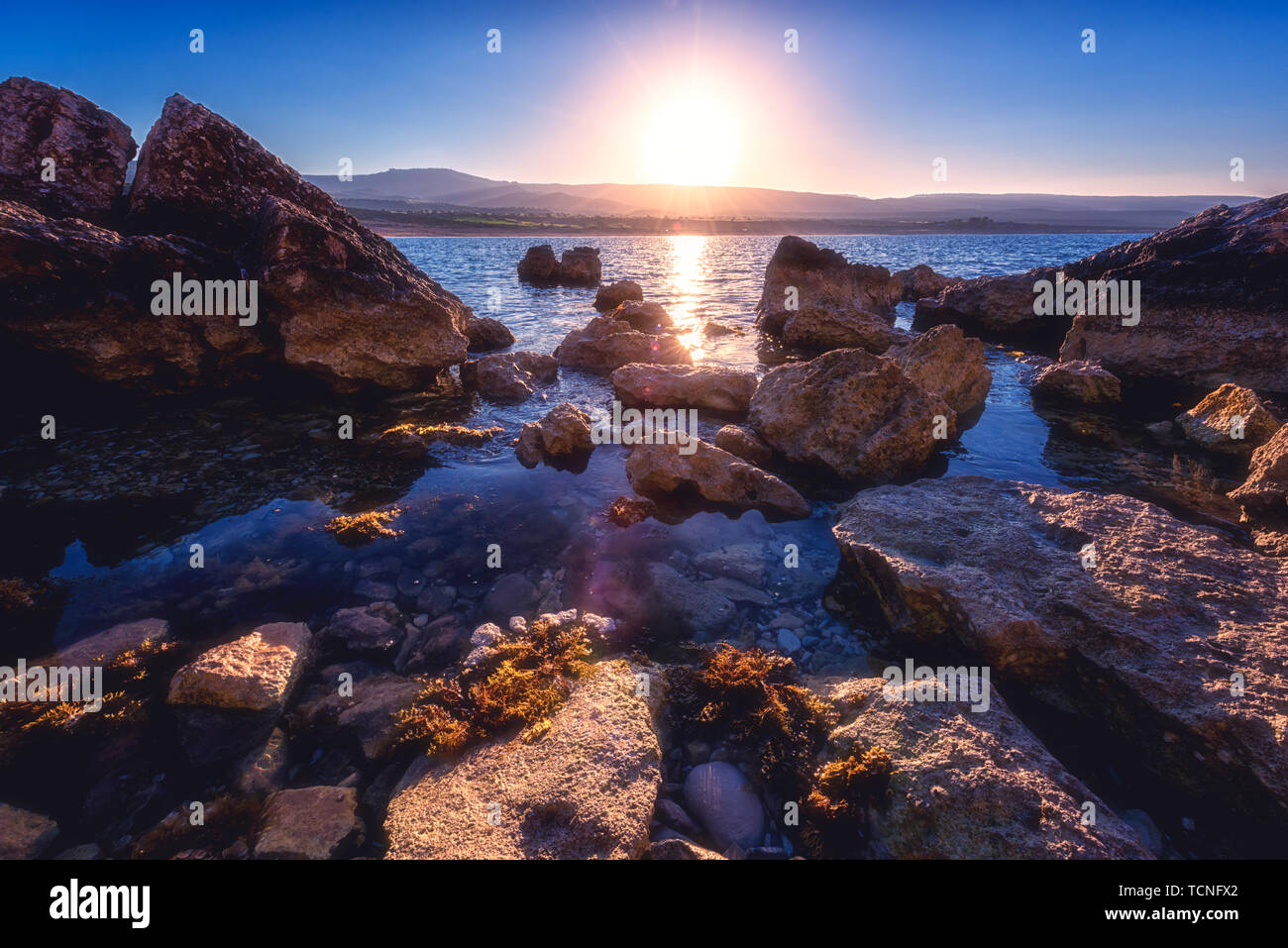 Una natura che stupisce seascape con Rising Sun oltre il litorale roccioso della penisola di Akamas, Cipro. Mare Mediterraneo vicino alla famosa spiaggia di Lara loc turistica Foto Stock