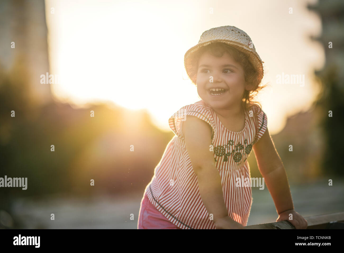 Ritratto di un simpatico bella e felice ragazza in piedi sulla panchina nel parco. Foto Stock
