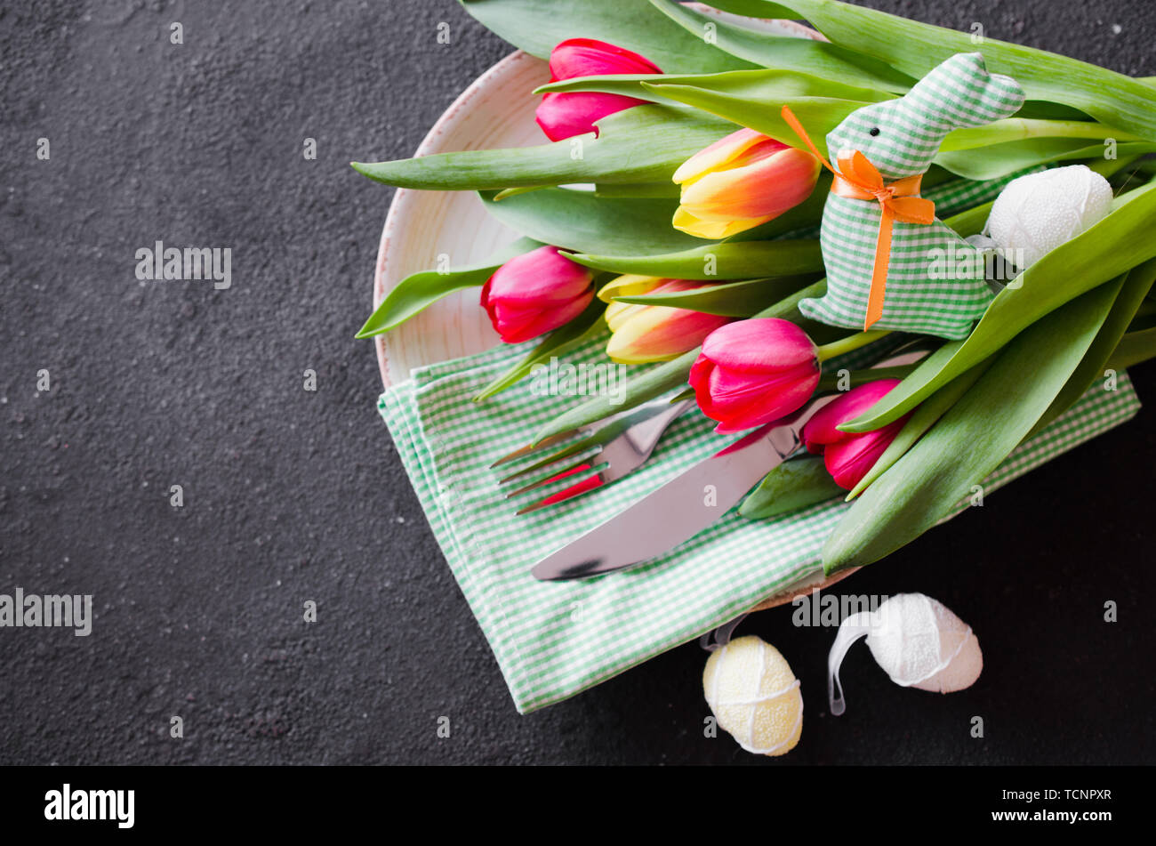 Pasqua messa in tavola con bouquet di tulipani e posate. Preparazione per la festosa cena di Pasqua. Vista dall'alto. Foto Stock
