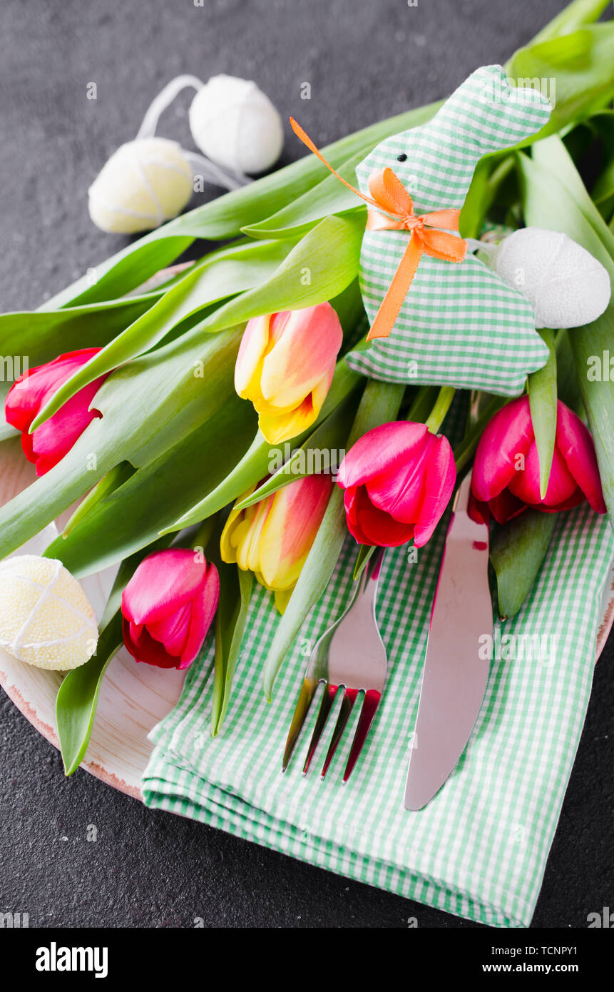 Pasqua messa in tavola con bouquet di tulipani e posate. Preparazione per la festosa cena di Pasqua. Vista dall'alto. Foto Stock