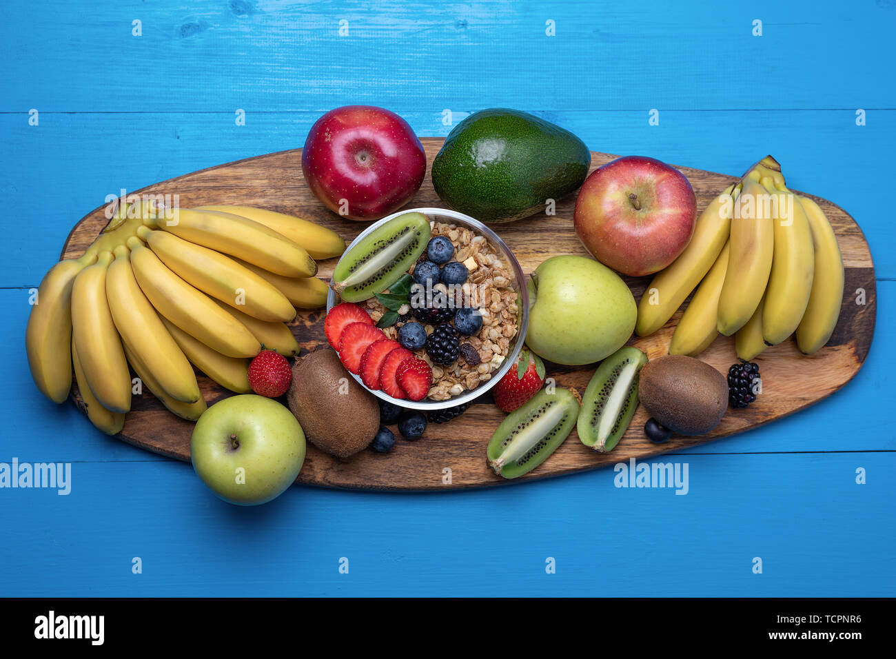 Vista superiore del brillante frutti assortiti, banane, mele, manghi, kiwi, fragole, mirtilli, con cereali per una sana prima colazione. Foto Stock