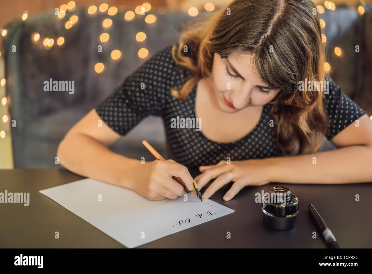 Elenco di cose da fare. Calligrapher giovane donna scrive una frase sul libro bianco. Inscrivendo ornamentali in lettere decorate. La calligrafia, graphic design, scritte Foto Stock