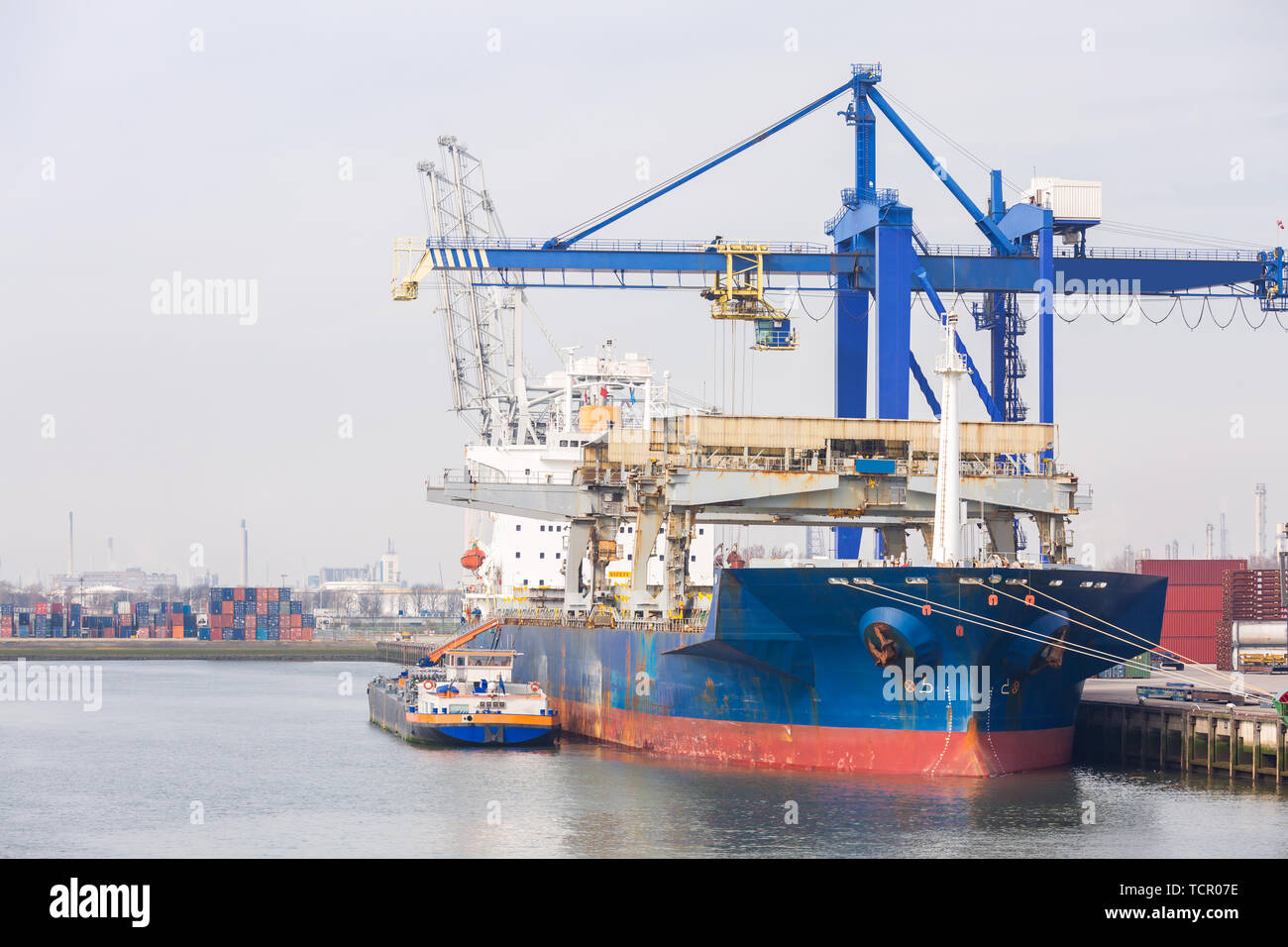 Grandi contenitori di carico barca con merci cargo pila presso il molo docks porto in attesa del mare internazionale il trasporto merci nel porto di Rotterdam delle Antille Foto Stock