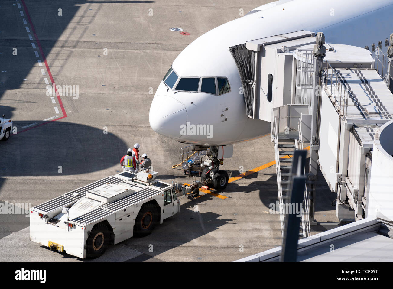 Aeroplano bianco lo scarico e il carico dei passeggeri a getto a ponte in aeroporto Foto Stock