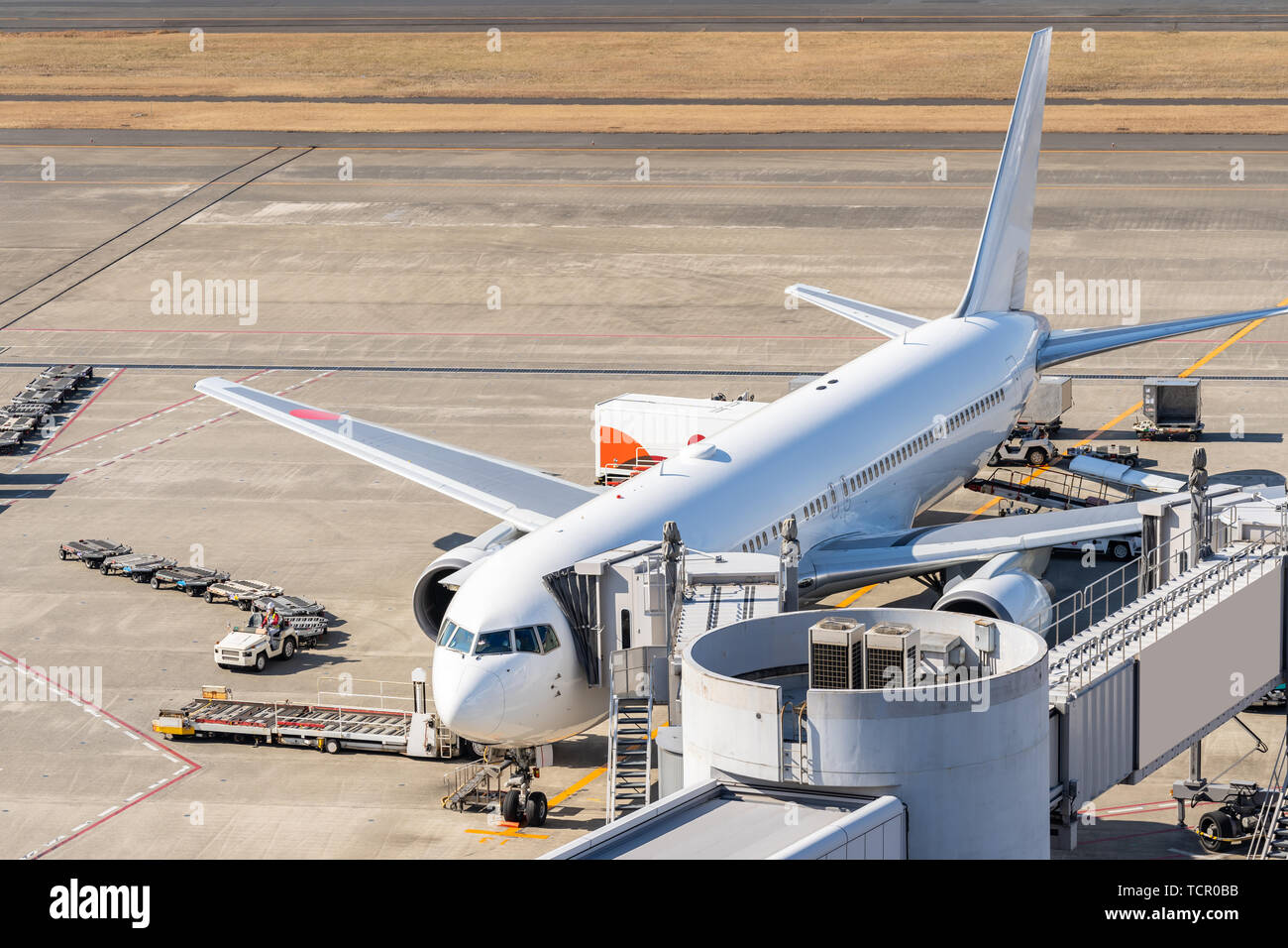 Aeroplano bianco lo scarico e il carico dei passeggeri a getto a ponte in aeroporto Foto Stock
