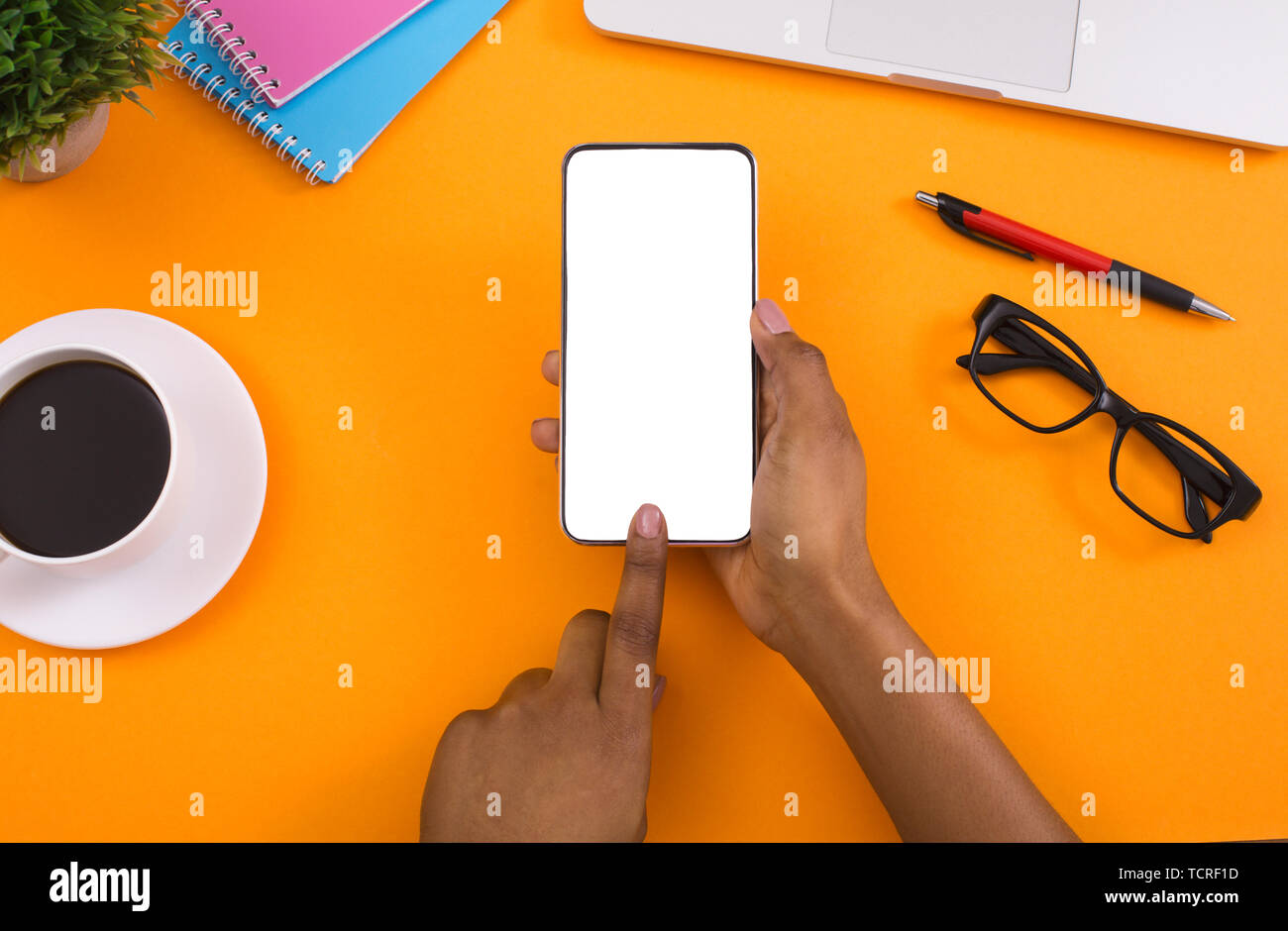 Donna che utilizza lo smartphone in bianco su sfondo arancione Foto Stock