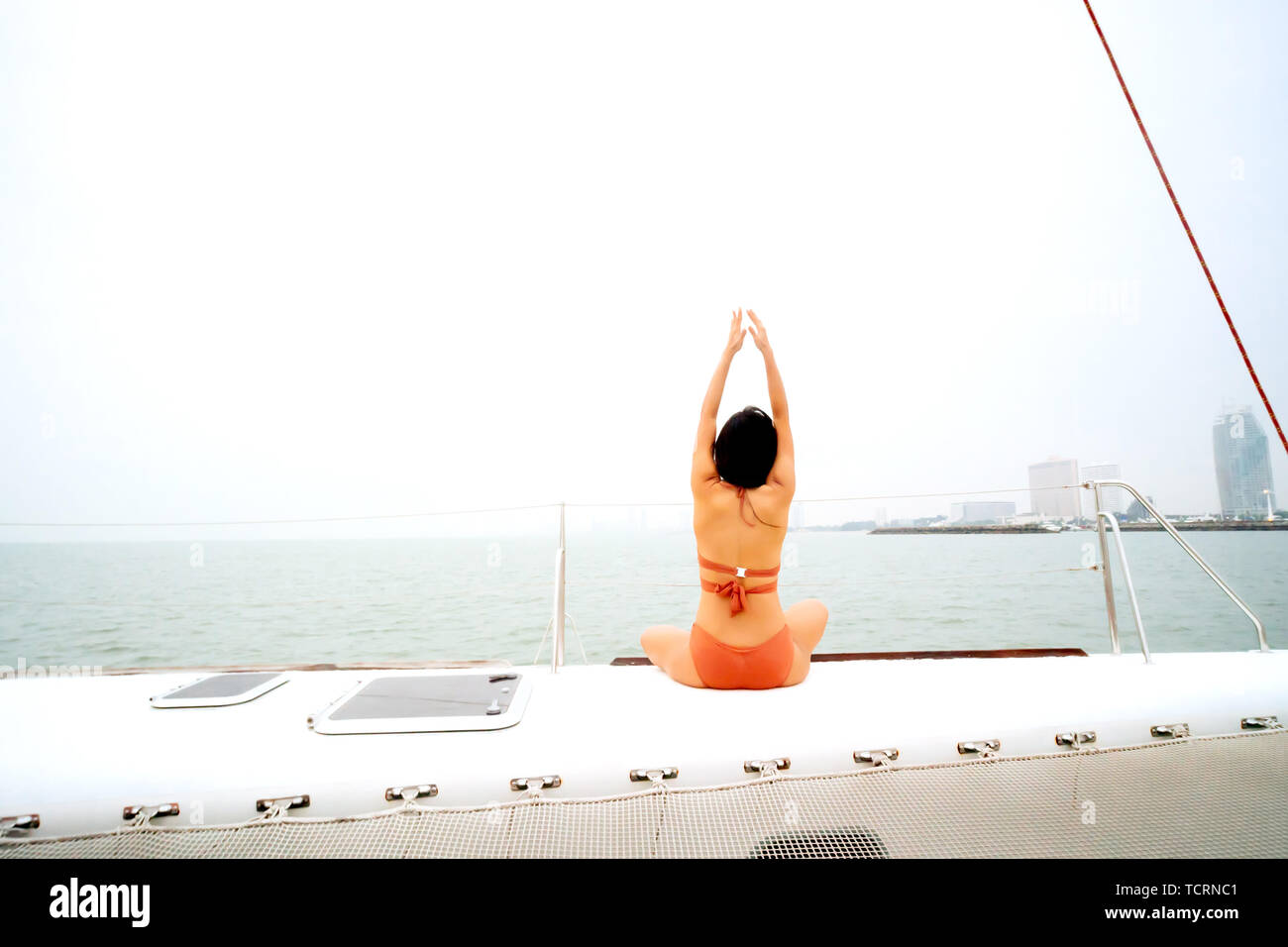 Retro di giovani sani e calma la donna a praticare lo yoga e la meditazione seduta con le mani su yacht a vela barca con mare oceano in background Foto Stock