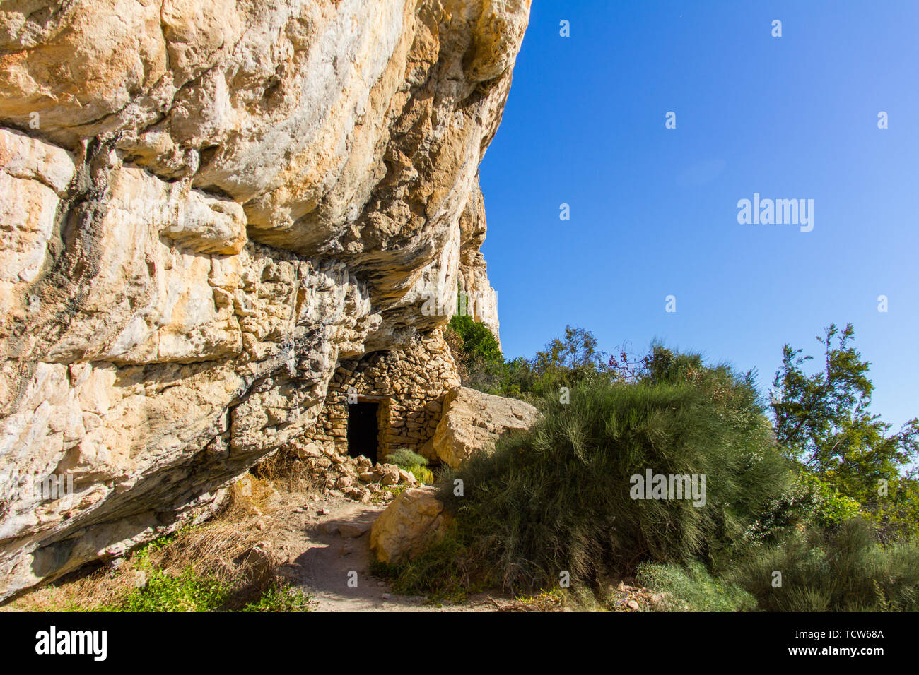 Vecchi pescatori grotta casa costruita su una rupe a Moraig beach, in Benitatxell, Spagna Foto Stock
