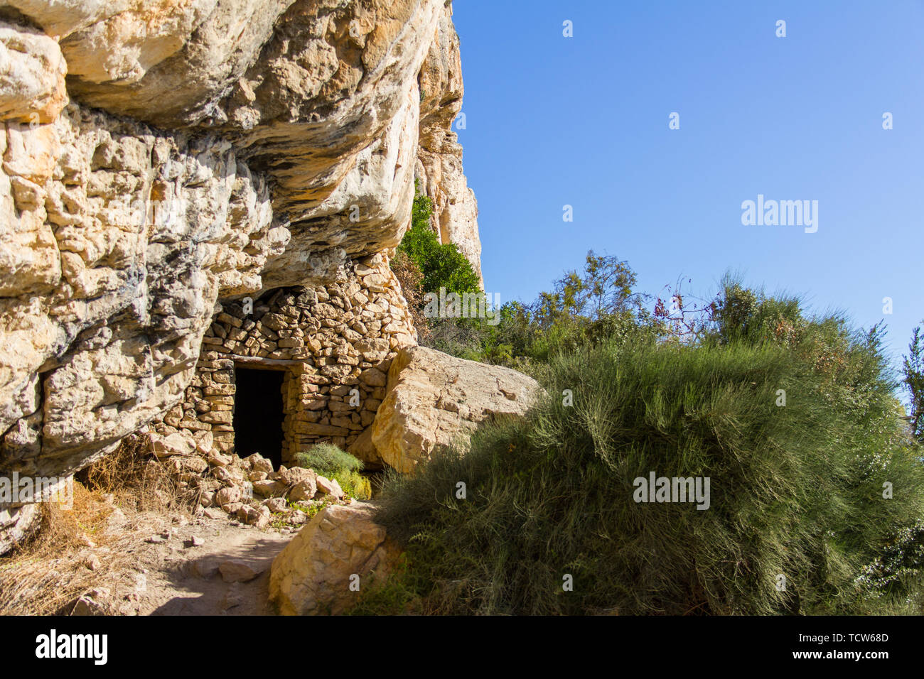 Antica grotta dei pirati casa costruita su una rupe a Moraig beach, in Benitatxell, Spagna Foto Stock