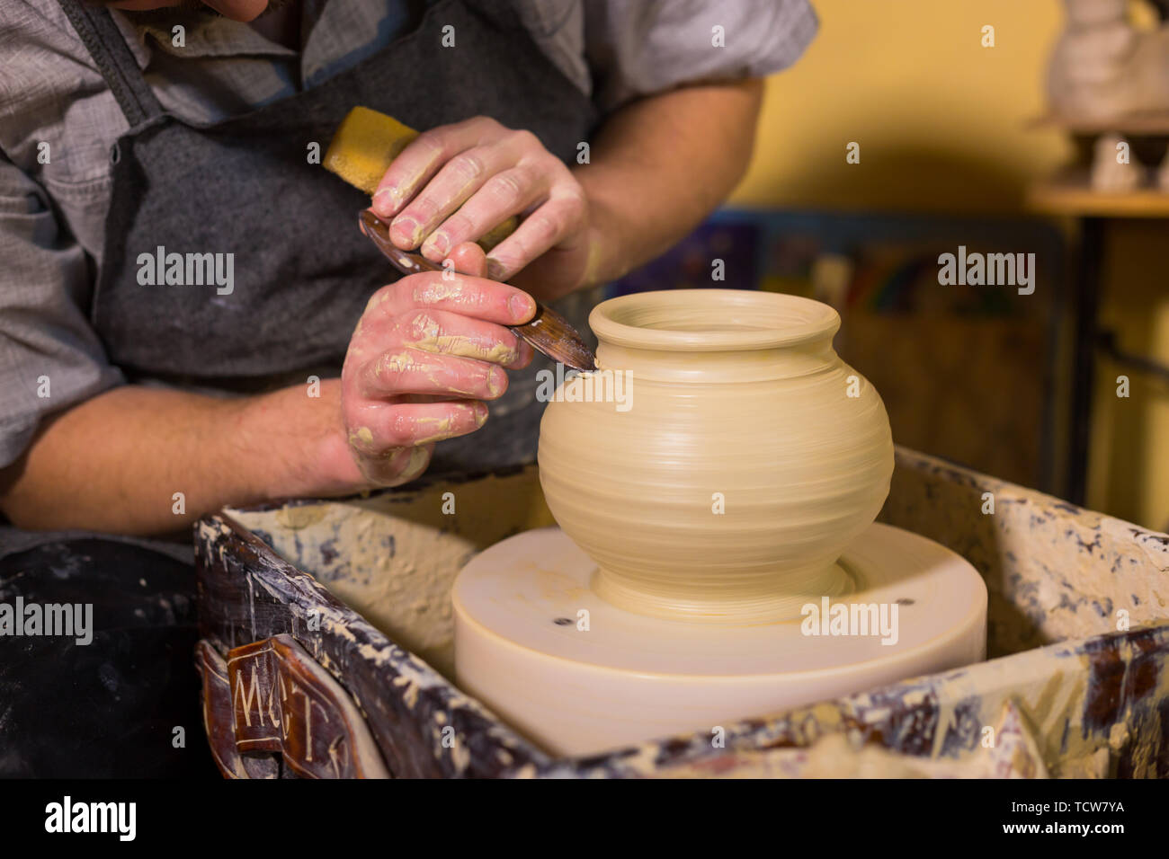 Professional potter carving pentola con l'attrezzo speciale nel laboratorio di ceramica Foto Stock