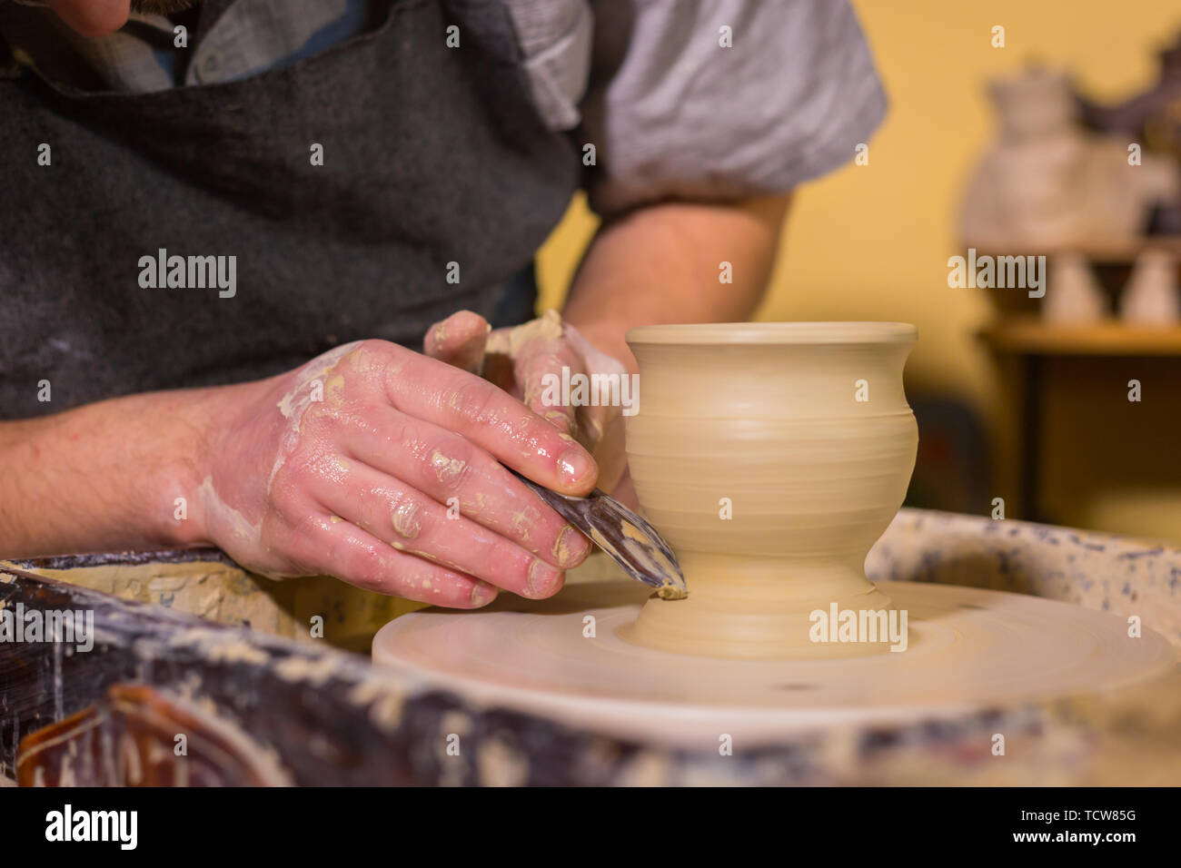Professional potter carving mug con l'attrezzo speciale nel laboratorio di ceramica Foto Stock