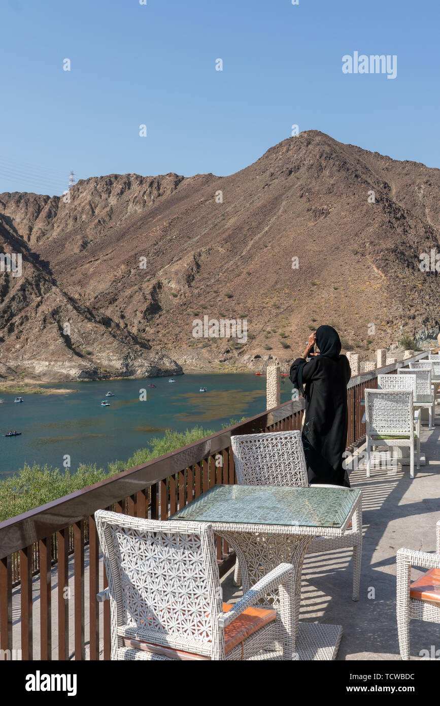 6 giugno 2019 - Khor Fakkan, UAE locale: ragazza araba prendendo le immagini del lago e delle barche Al Rafisha Dam, Khor Fakkan Foto Stock