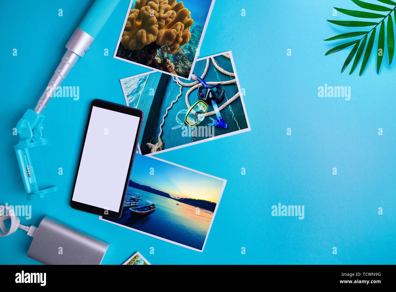 Smartphone con schermo vuoto e volantini e foto su uno sfondo blu. Mock up, piatto laici. La vacanza estiva concetto. Foto Stock