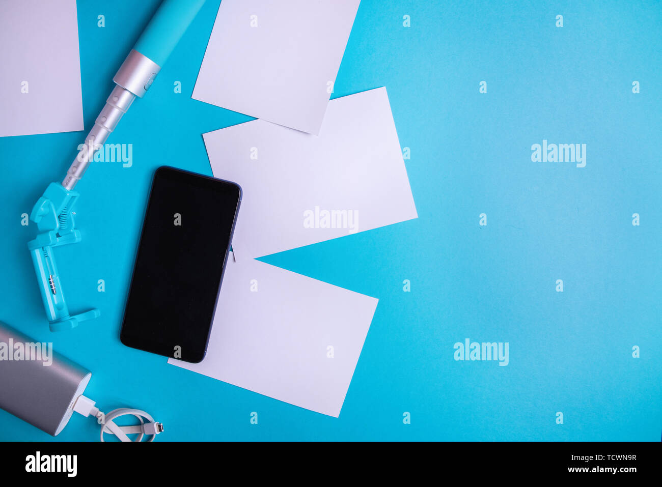 Smartphone con schermo vuoto e volantini e foto su uno sfondo blu. Mock up, piatto laici. La vacanza estiva concetto. Foto Stock