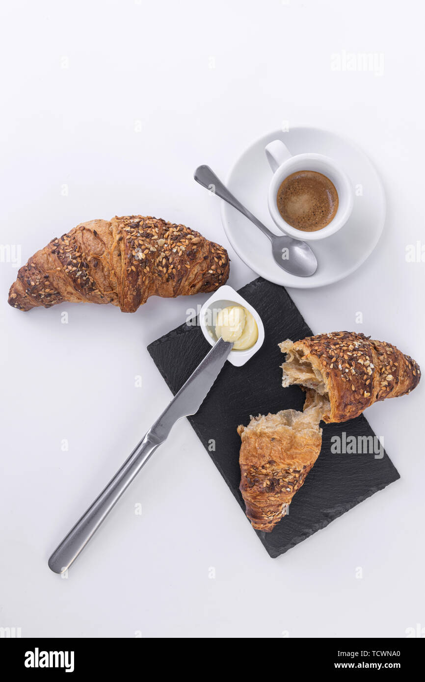 Due cornetti con semi di sesamo, semi di caffè caldo e burro fresco per la prima colazione. Foto Stock