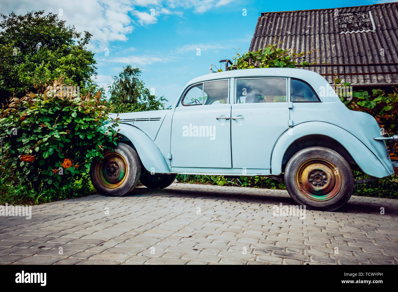Molto vecchia auto su uno sfondo di fiori Foto Stock