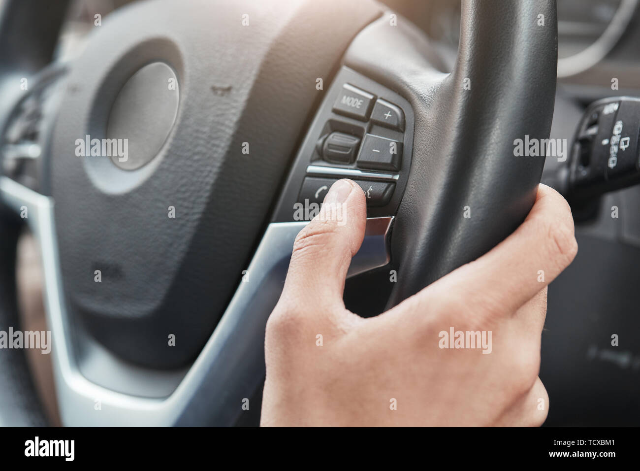 La nuova vettura. Immagine ritagliata una mano che spinge i tasti di comando sul volante in una moderna autovettura. Lato conducente. Unità di prova Foto Stock