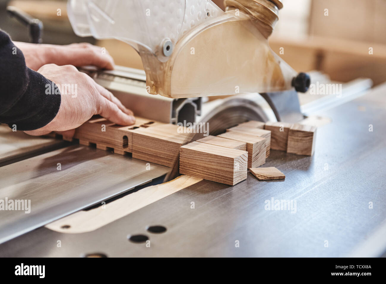 Immagine ritagliata delle mani di un artigiano il taglio di una trave di legno con una sega circolare in un workshop Foto Stock