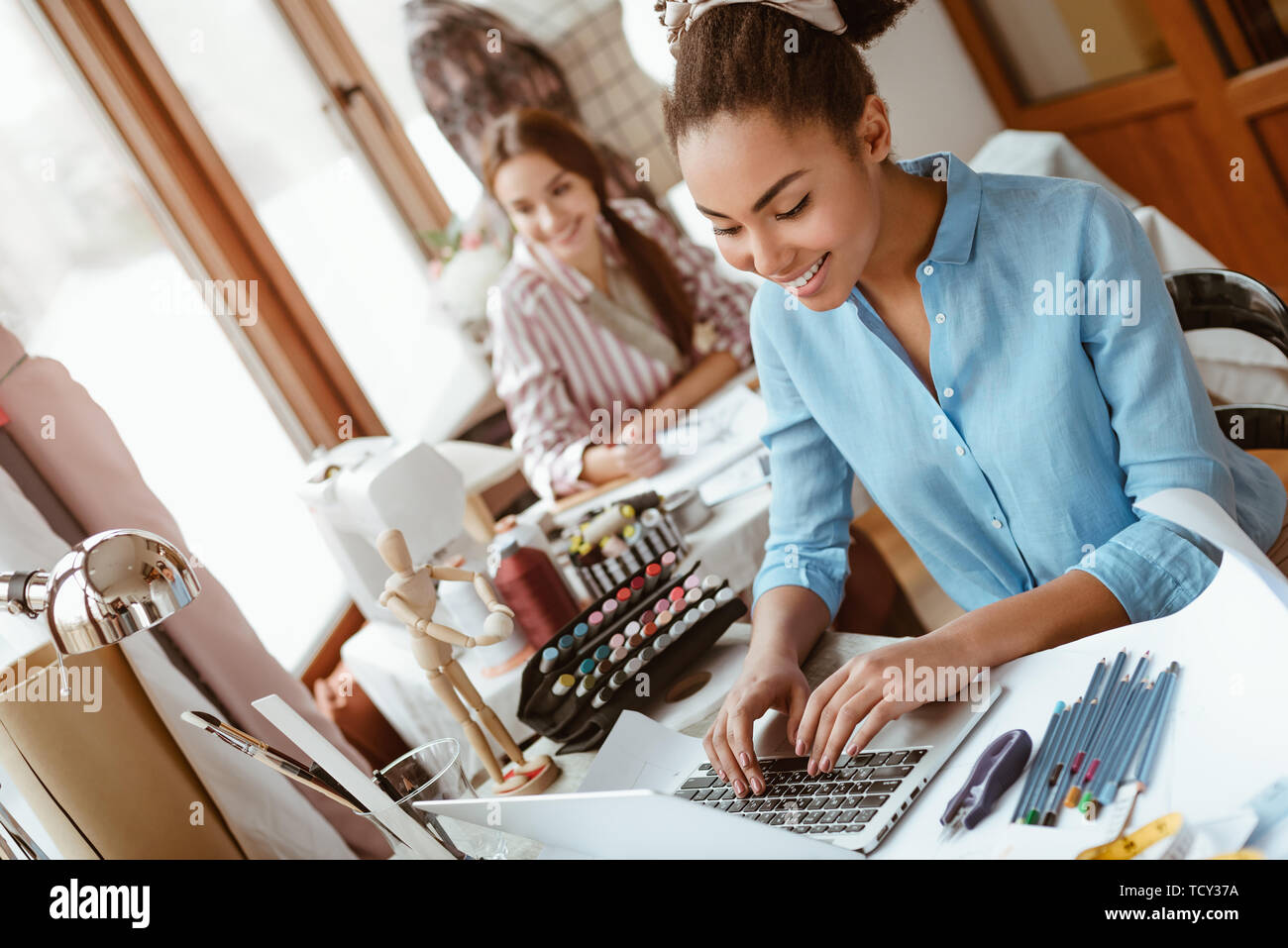 Tenendo il divertimento in studio di design. Close-up di due giovani donne attraenti a lavorare su un nuovo progetto di design. Giovane donna africana in primo piano e caucasico Foto Stock