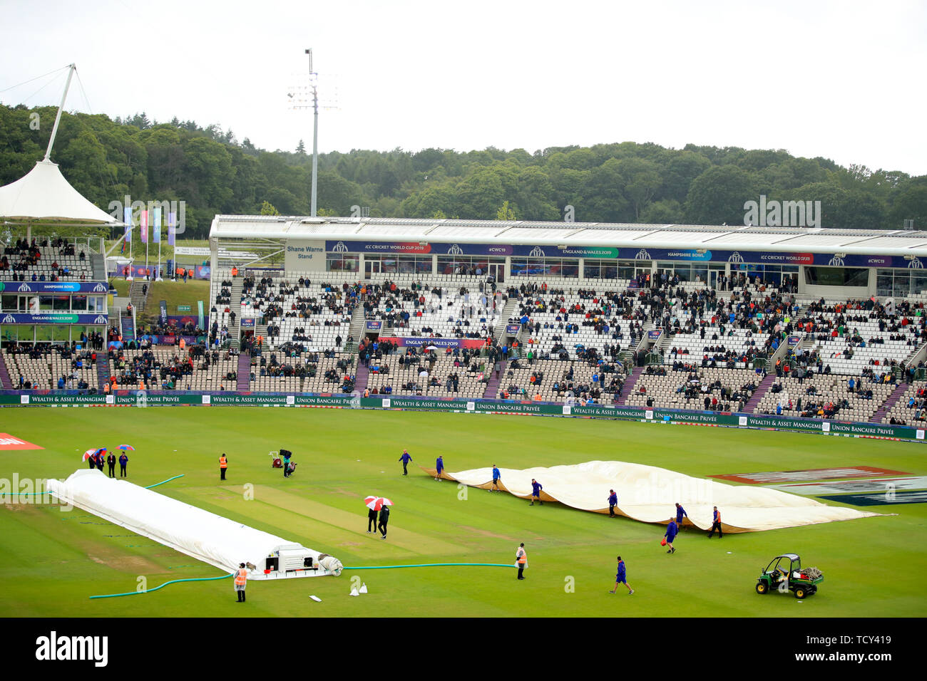 Corrispondono i funzionari e il personale di terra mettere le coperture rain torna su durante la ICC Cricket World Cup group stage corrispondono a Hampshire ciotola, Southampton. Foto Stock