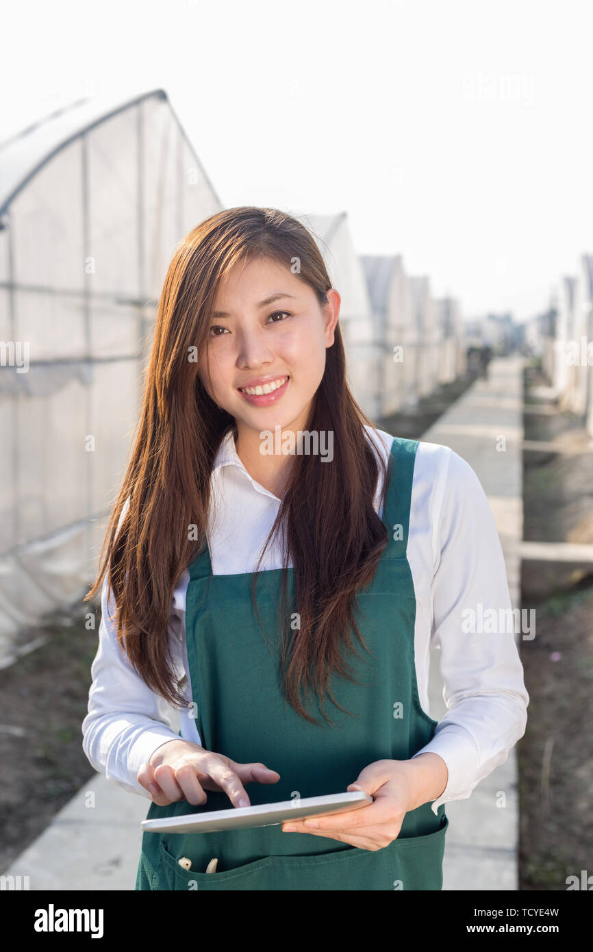 Giovane bella donna asiatica lavora nel campo verde Foto Stock