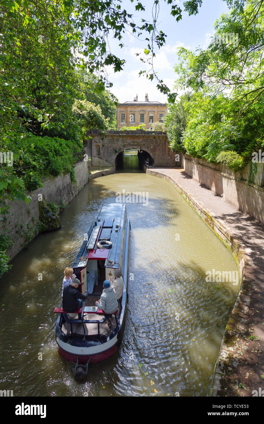 Bath Somerset England Regno Unito ; il Kennet and Avon Canal, - un canal boat andare sotto un ponte su una soleggiata giornata estiva in giugno, bagno England Regno Unito Foto Stock