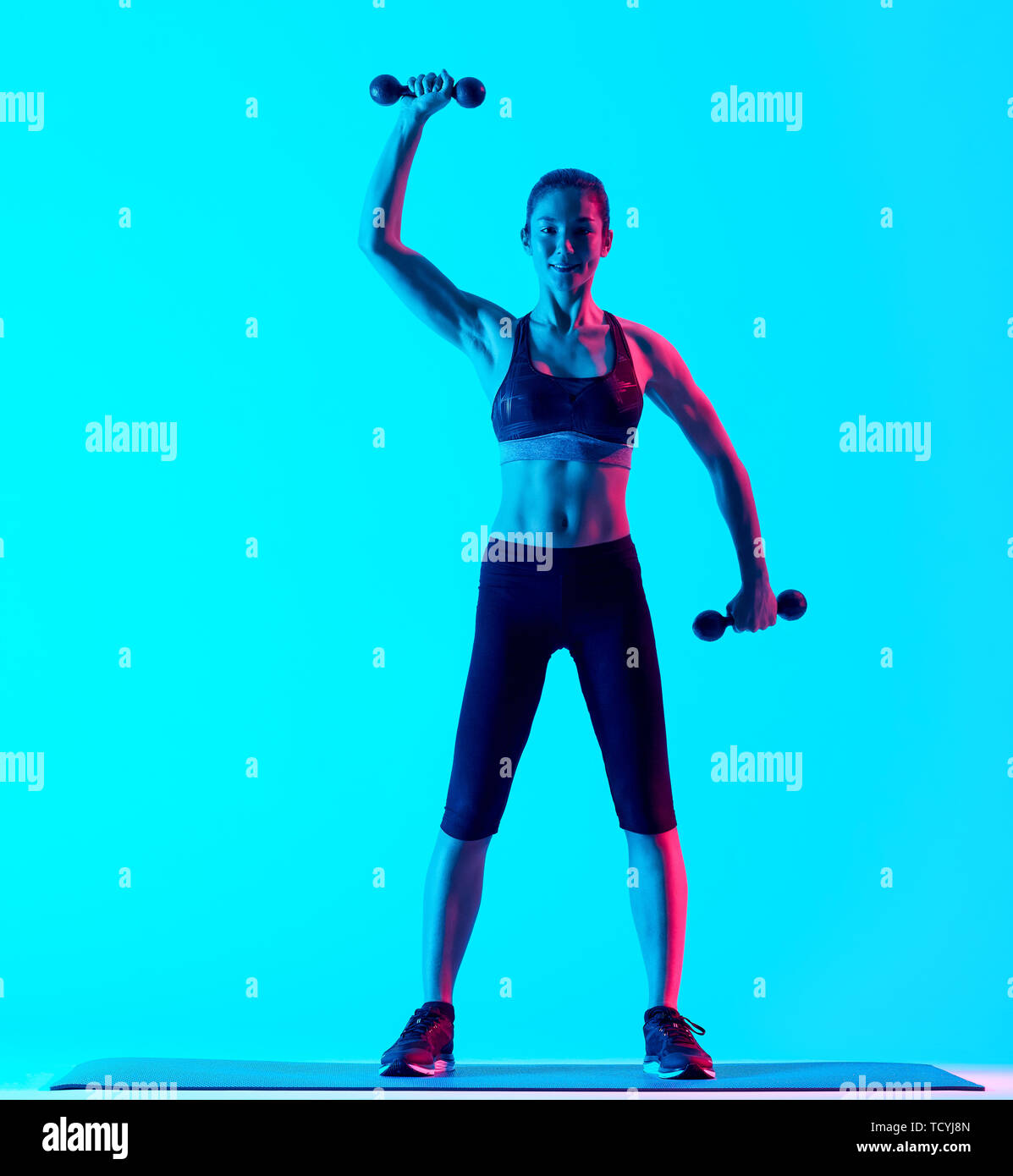 Una mista gare donna exercsing pesi esercizi fitness isolate su blackground blu Foto Stock