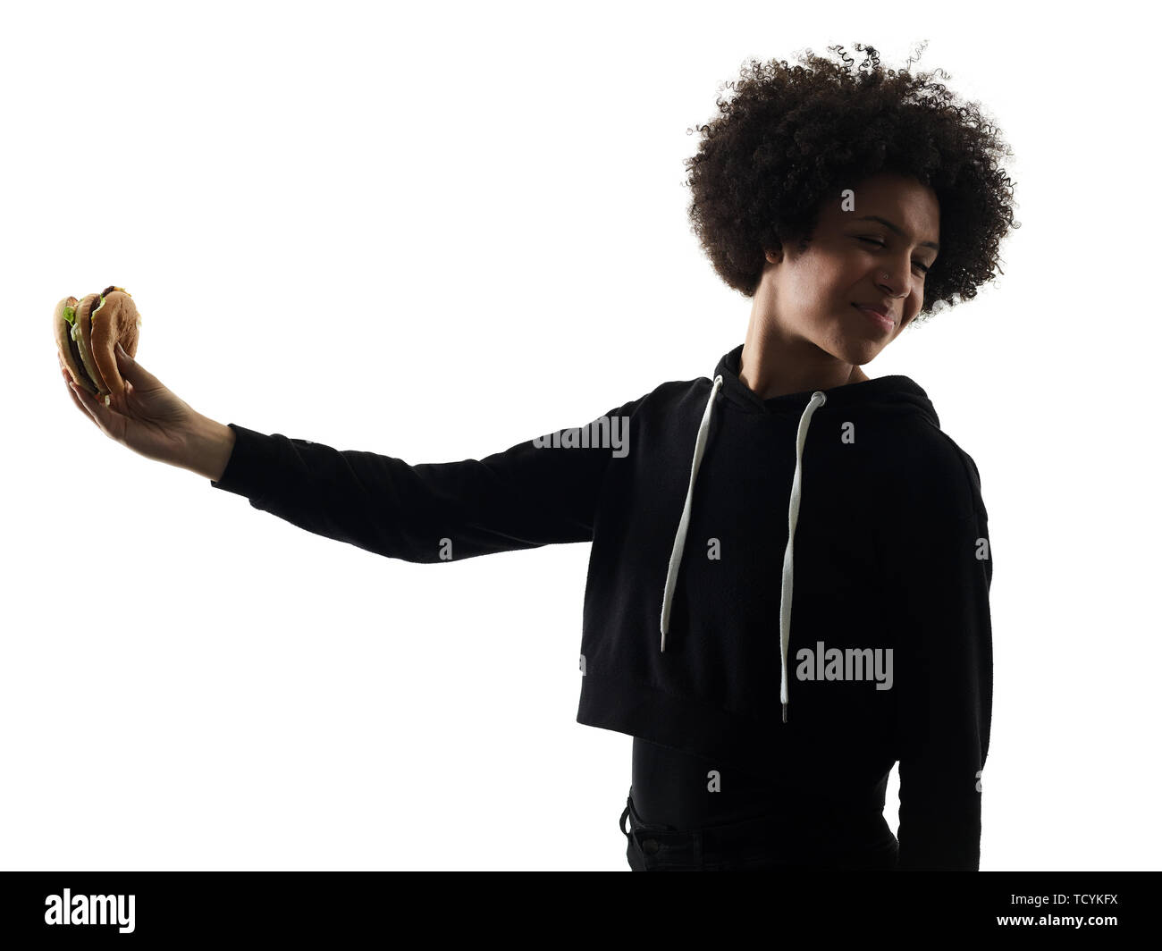 Una razza mista africana di adolescente Ragazza donna mangiare hamburger in studio ombra silhouette isolati su sfondo bianco Foto Stock