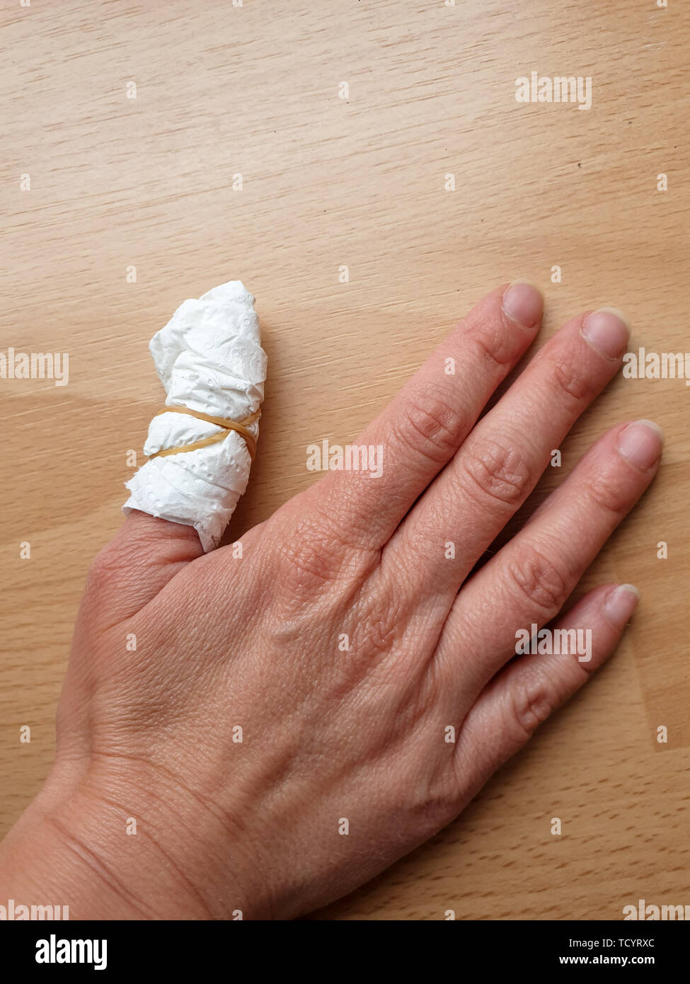 Immagine del bendaggio bianco su imjured pollice su sfondo di legno Foto Stock