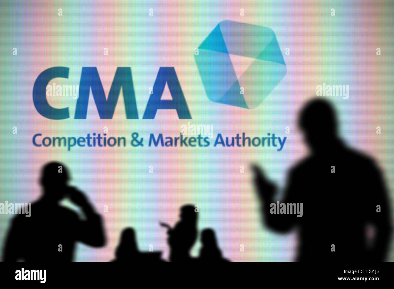 Il logo di CMA è visto su uno schermo a LED in background mentre si profila una persona utilizza uno smartphone in primo piano (solo uso editoriale) Foto Stock