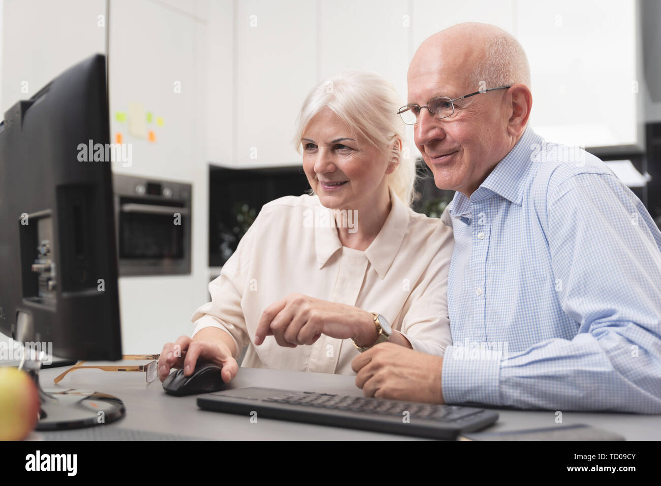 Felice vecchio paio di godere insieme al computer. Gli anziani utilizzano un computer, essi guardare le foto che hanno ricevuto. Foto Stock