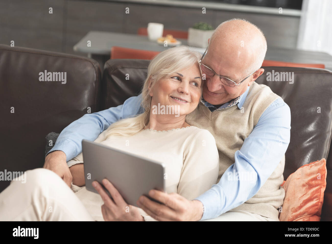 Coppia senior con tavoletta digitale a casa. Nonni con i social media. Foto Stock