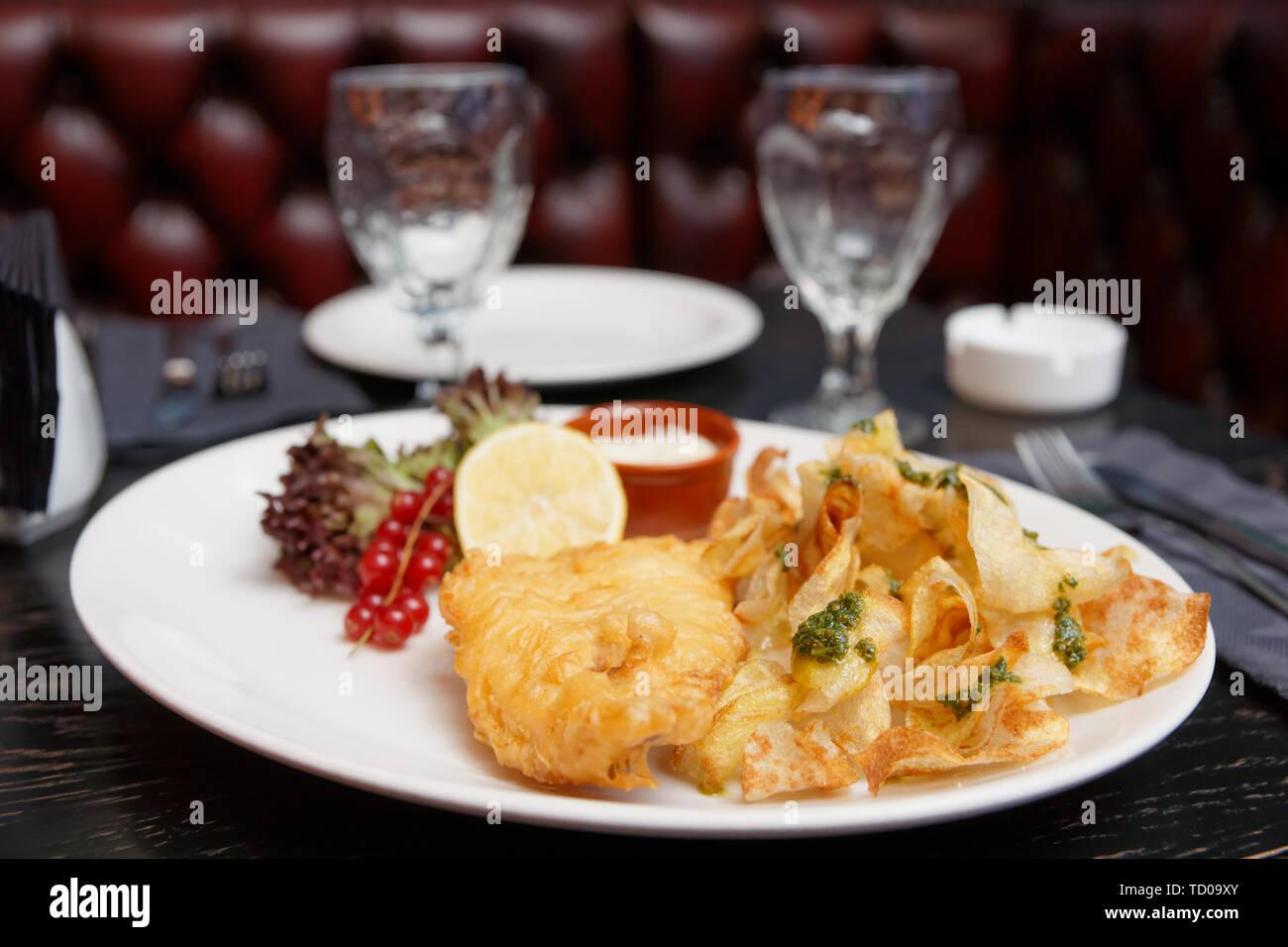 Pesce e patatine in piastra disposta sul tavolo in stile pub Foto Stock