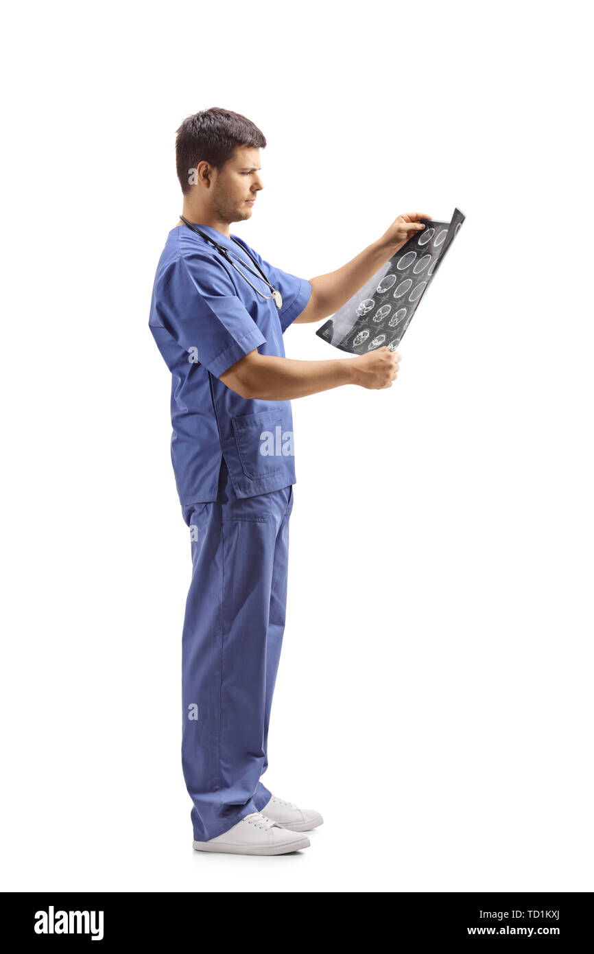 Lunghezza piena ripresa del profilo di un giovane maschio medico in uniforme blu guardando immagine a raggi x isolato su sfondo bianco Foto Stock