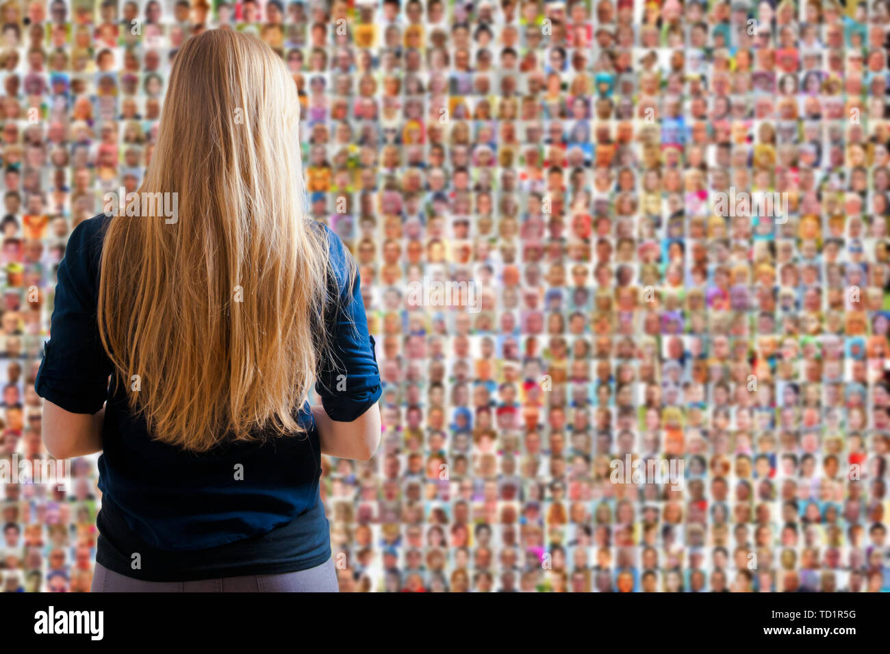 Donna bionda di fronte a uno schermo o a parete con migliaia di persone si affaccia- social network e social media concept Foto Stock