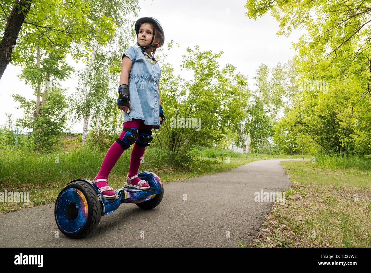 Bambina a cavallo di un auto elettrica-scooter di bilanciamento. bambino è in equilibrio su un gyroscooter. Personale di trasporto eco, giroscopio scooter, smart ruota di equilibrio Foto Stock