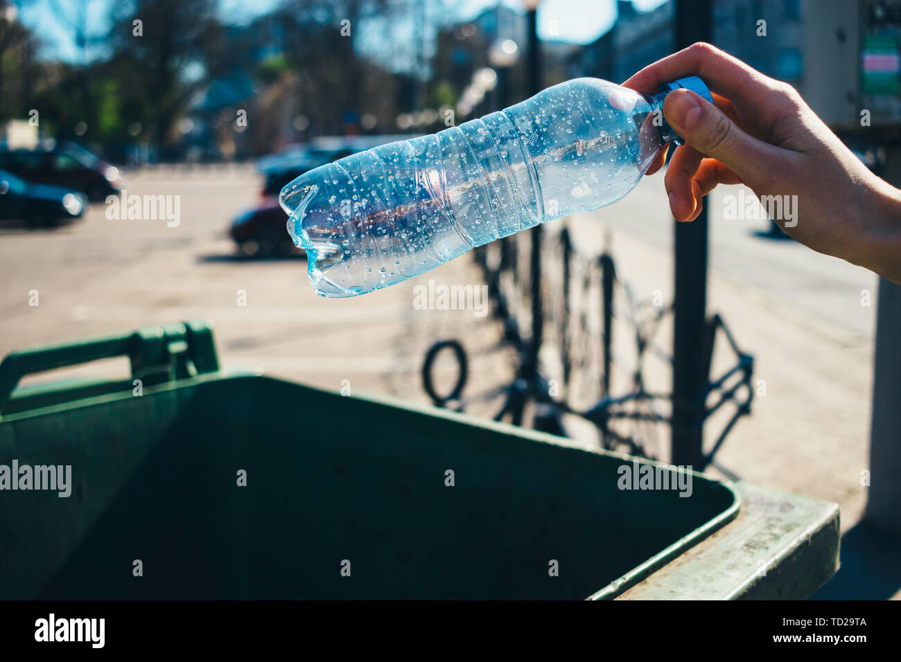 Donna di lancio a mano in plastica vuoto bottiglia di acqua nel cestino nella città di close-up. Foto Stock
