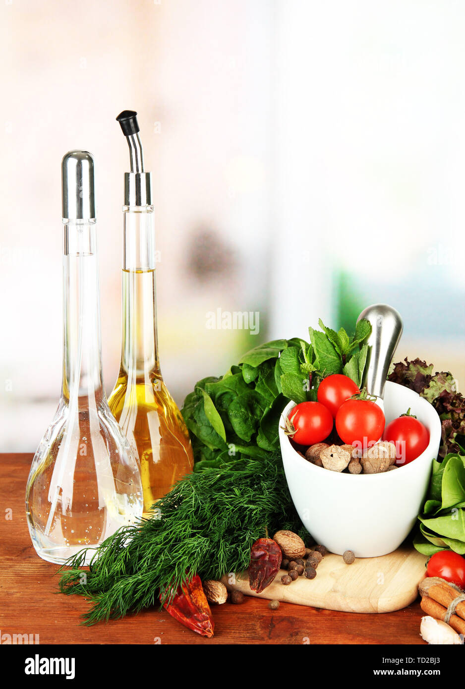 Composizione del mortaio, bottiglie con olio di oliva e aceto, e verde erboristeria, su sfondo lucido Foto Stock