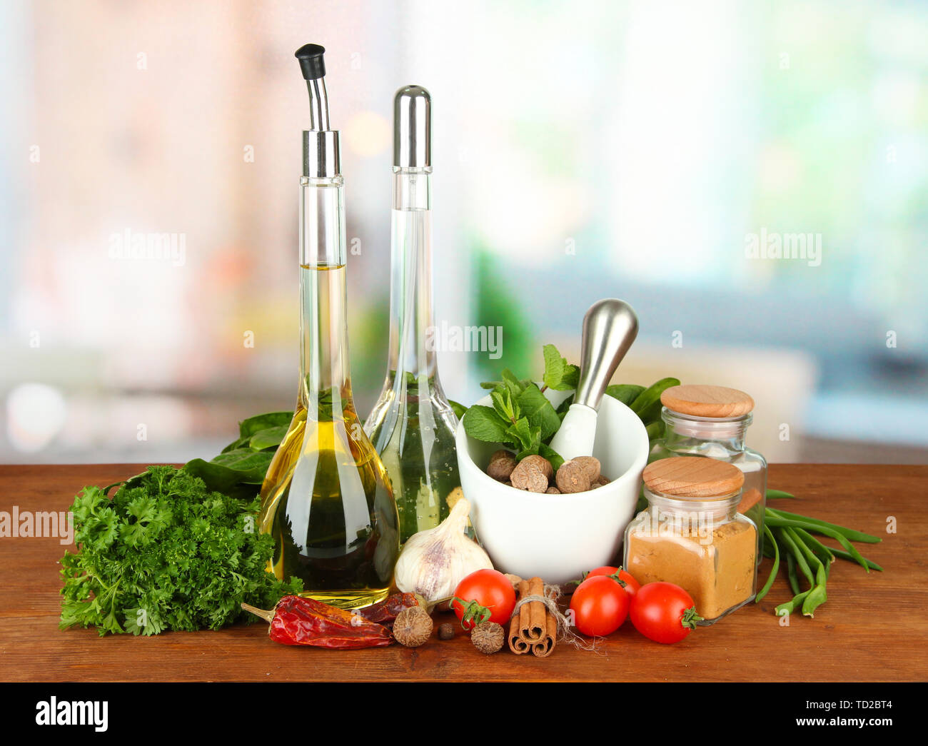 Composizione del mortaio, bottiglie con olio di oliva e aceto, e verde erboristeria, su sfondo lucido Foto Stock