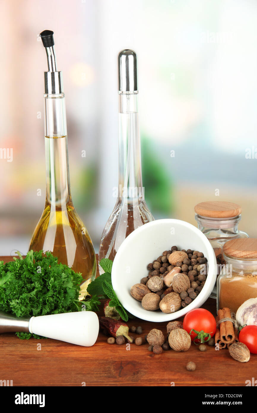 Composizione del mortaio, bottiglie con olio di oliva e aceto, e verde erboristeria, su sfondo lucido Foto Stock