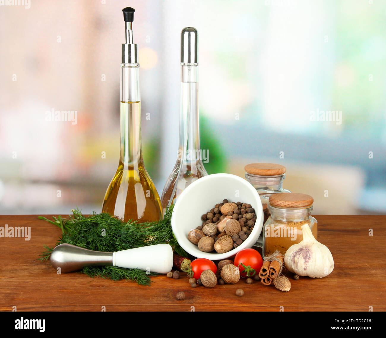 Composizione del mortaio, bottiglie con olio di oliva e aceto, e verde erboristeria, su sfondo lucido Foto Stock