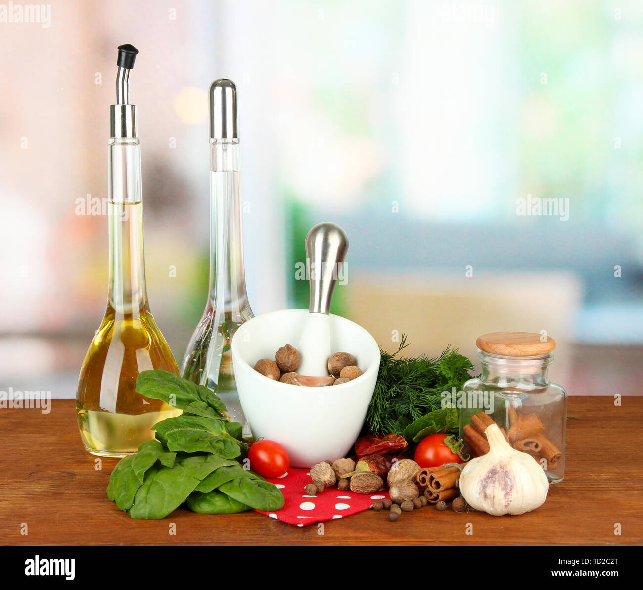 Composizione del mortaio, bottiglie con olio di oliva e aceto, e verde erboristeria, su sfondo lucido Foto Stock