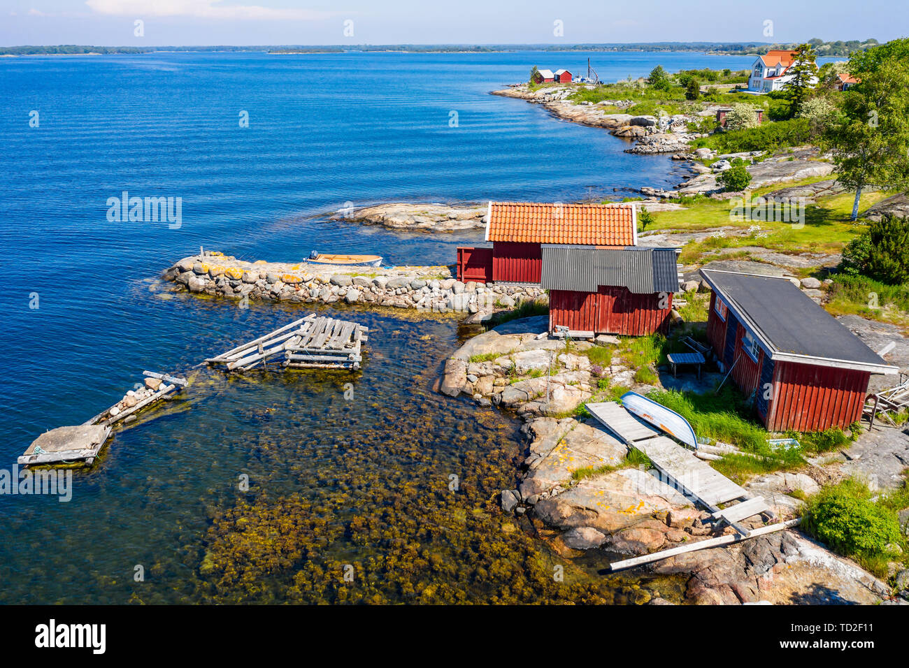 Isola litorale con rosso pesca in legno capannoni e molo di pietra. Ubicazione Hasslo isola nell'arcipelago di Blekinge, Svezia. Foto Stock