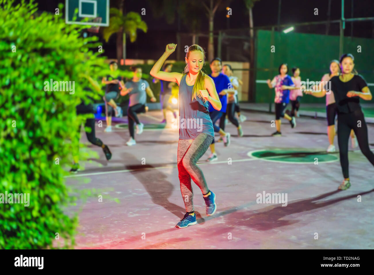 Giovane donna di un gruppo di allenamento sul campo di pallacanestro di sera Foto Stock Giovane donna di un gruppo di allenamento sul campo di pallacanestro di sera Foto Stock