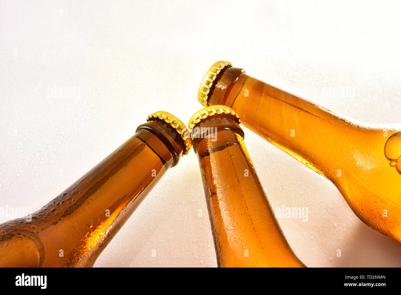 Tre colli di bottiglia riempita con birra fresca chiuso su un tavolo bianco con gocce d'acqua. Composizione orizzontale. Vista frontale. Foto Stock